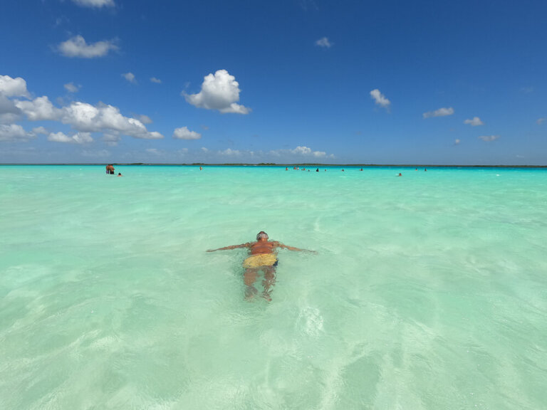 Man in yellow swim shorts floating in clear turquoise water