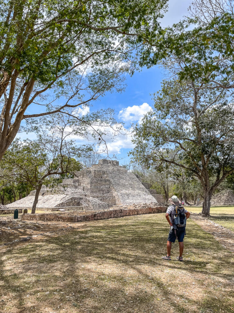 A man in a hat looks at ancient Mayan ruins of a temple