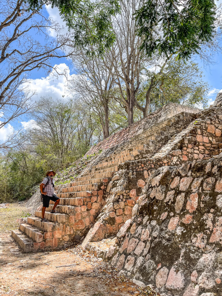 A man stands on a steep stone stairway with trees in the background