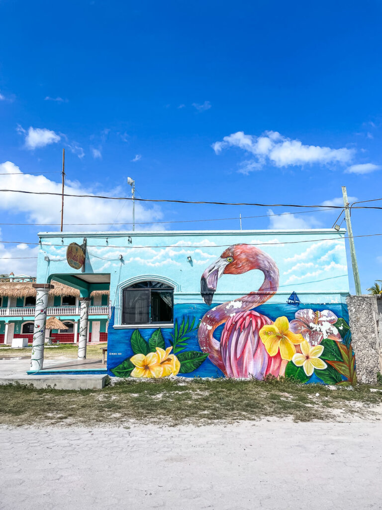 Colorful mural with a large pink flamingo and yellow flowers on a blue background