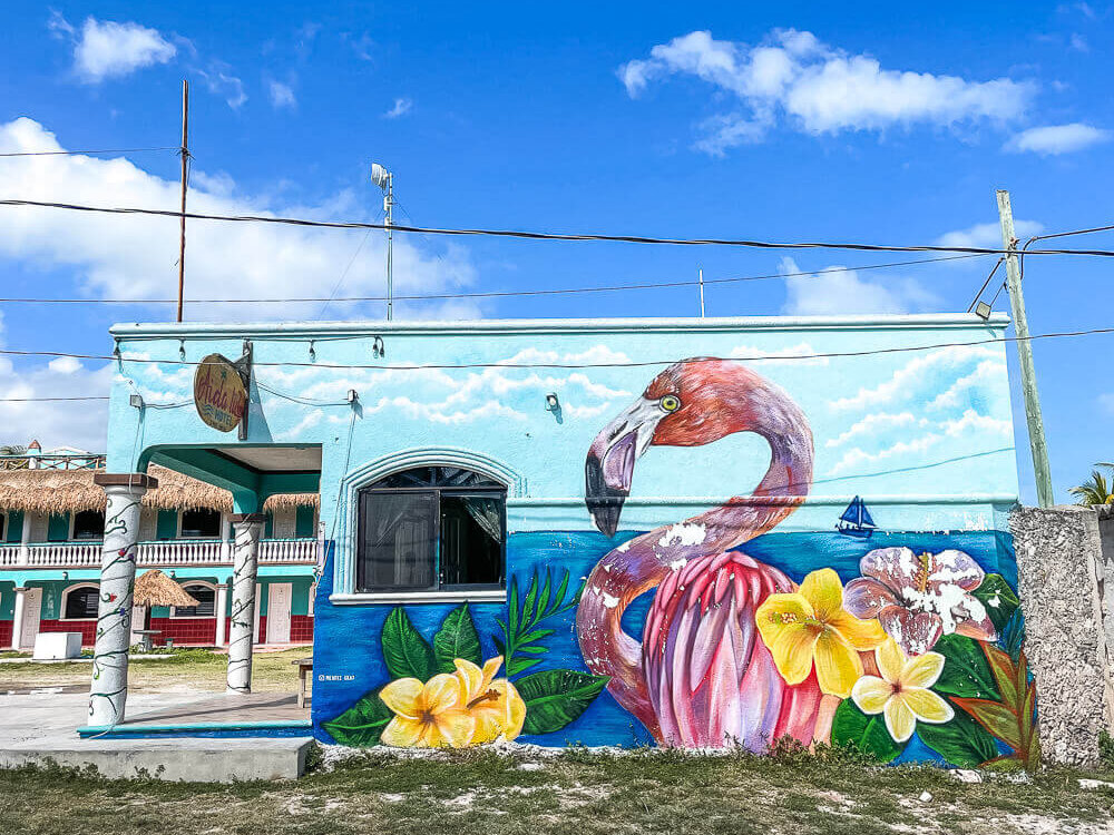 Colorful mural with a large pink flamingo and yellow flowers on a blue background