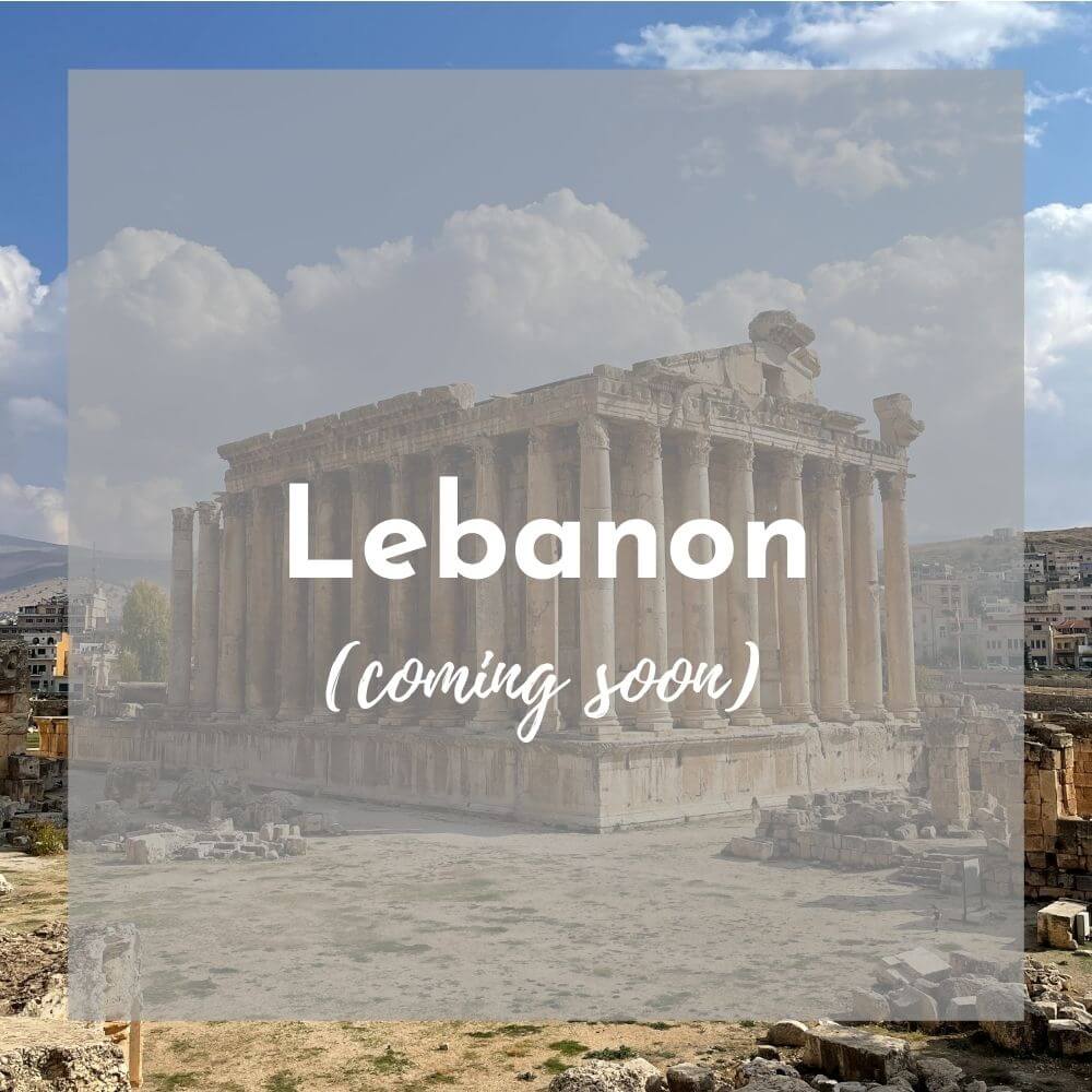 Foreground: a transparent grey box with Lebanon (coming soon) in white text Background photo: an ancient Roman temple with many columns and a gently sloping roofline stands against a blue sky with puffy clouds