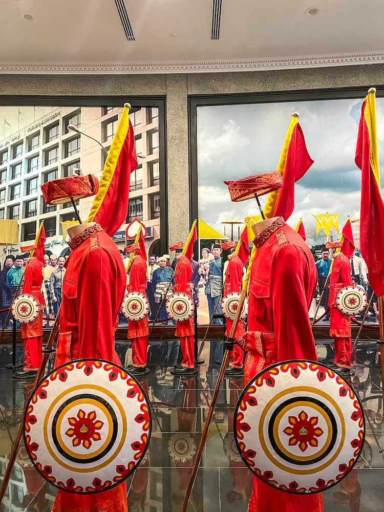 A close up of a mannequins dressed in a red uniform, holding a white shield with patterns.