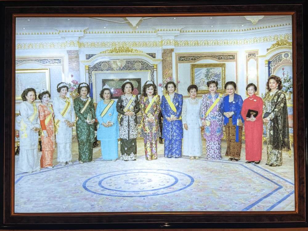 A photo of a row of colorfully dressed women in an ornate room