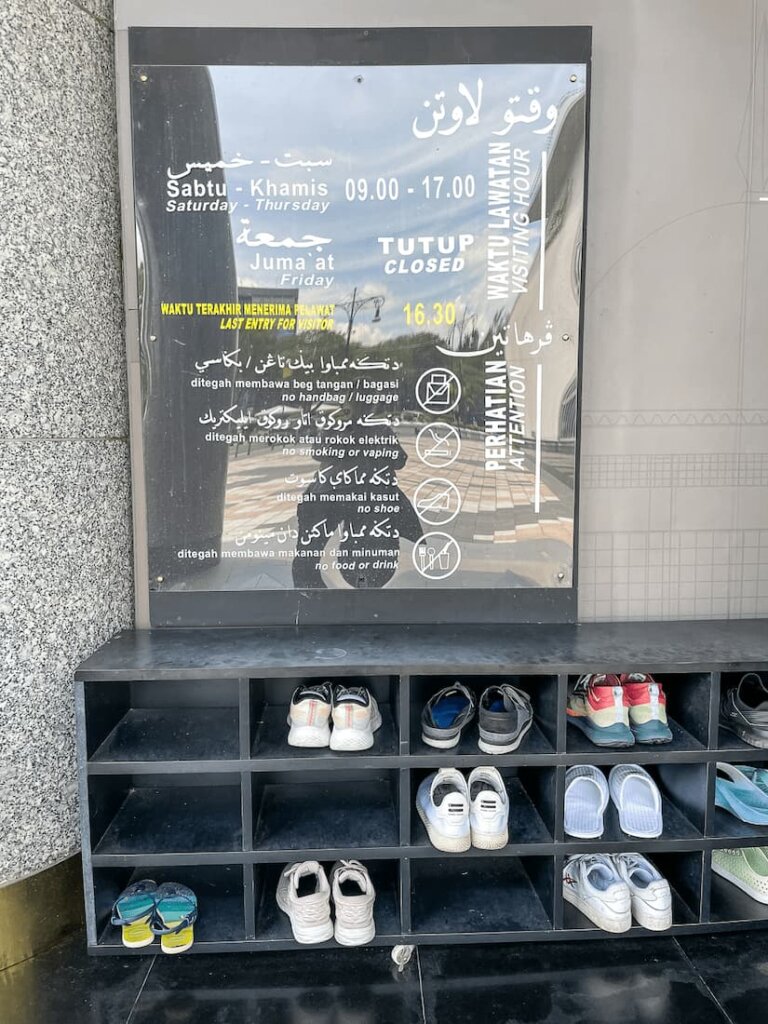 A large sign (difficult to read because of reflections) above a cabinet with shoes.