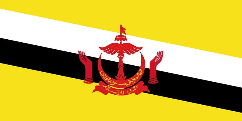 The Brunei flag has a yellow background with white and black stripes running horizontally from upper left to lower right. Brunei’s national coat of arms (a crescent under an umbrella, with hands on either side) is in red in the center of the flag.