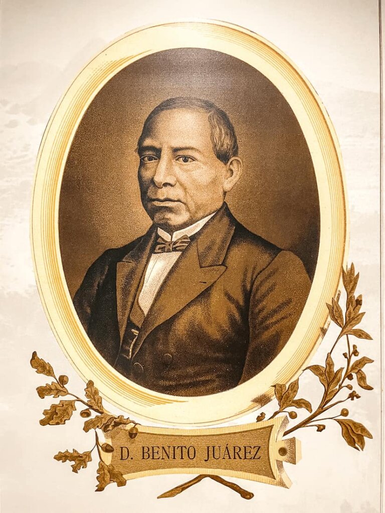 A sepia photograph of a man in a suit. The photograph is in an oval frame with images of leaves below.