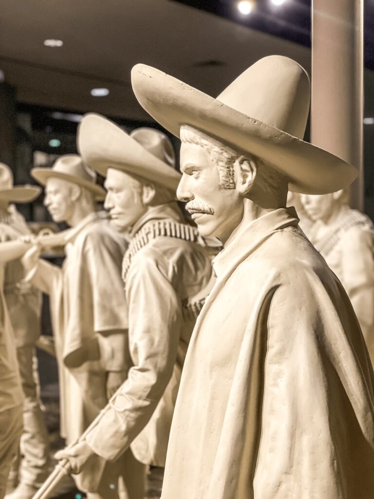 Side view of white statues of men with serious faces wearing sombreros