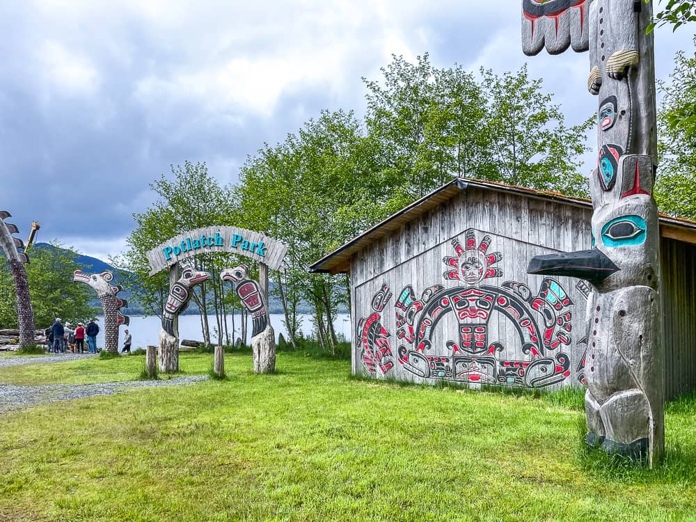 A wooden house decorated with native Alaskan paintings and a sign that says Potlatch Park.