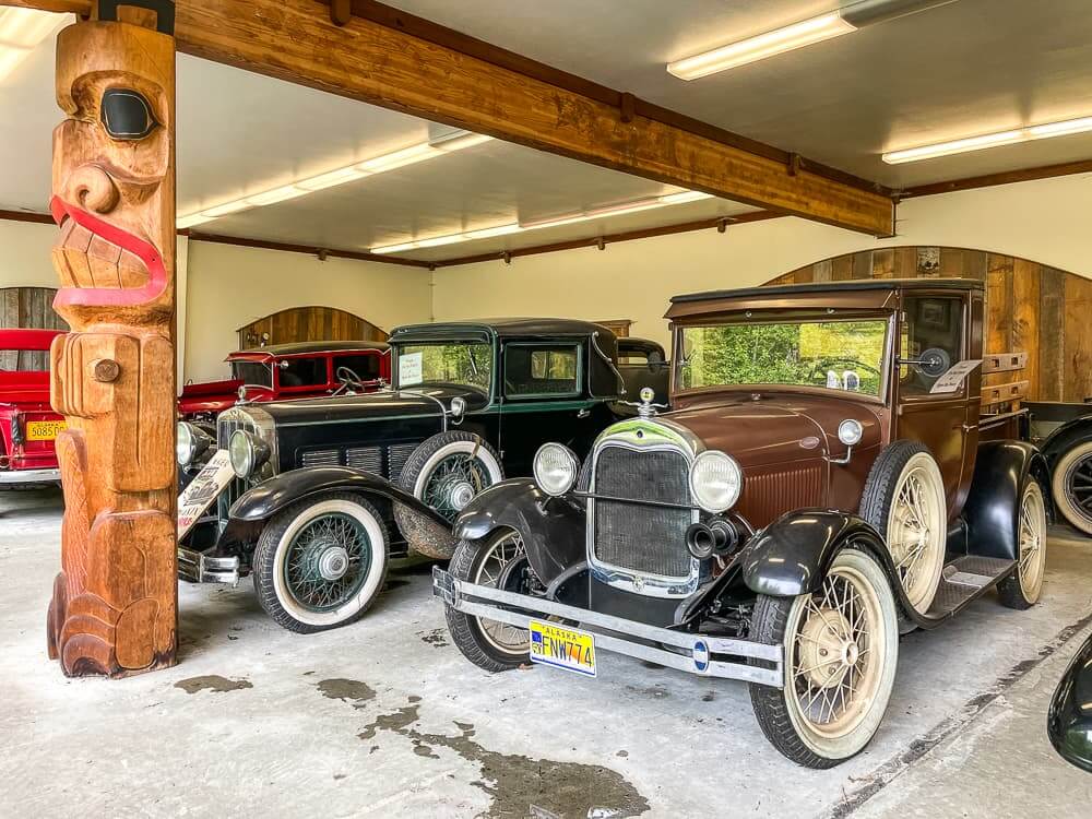 A row of vintage cars. The one in front is dark brown with white rimmed tires.