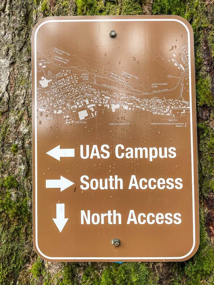 A brown sign with white writing. The sign has a map at the top, an arrow pointing left to UAS Campus, an arrow pointing right to South Access, and an arrow pointing down to North Access.