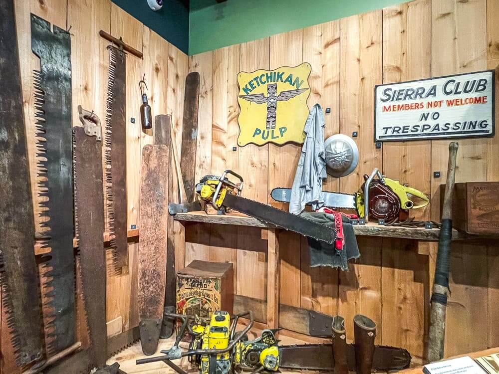 Old tools and signs hang from a wood panel wall. 