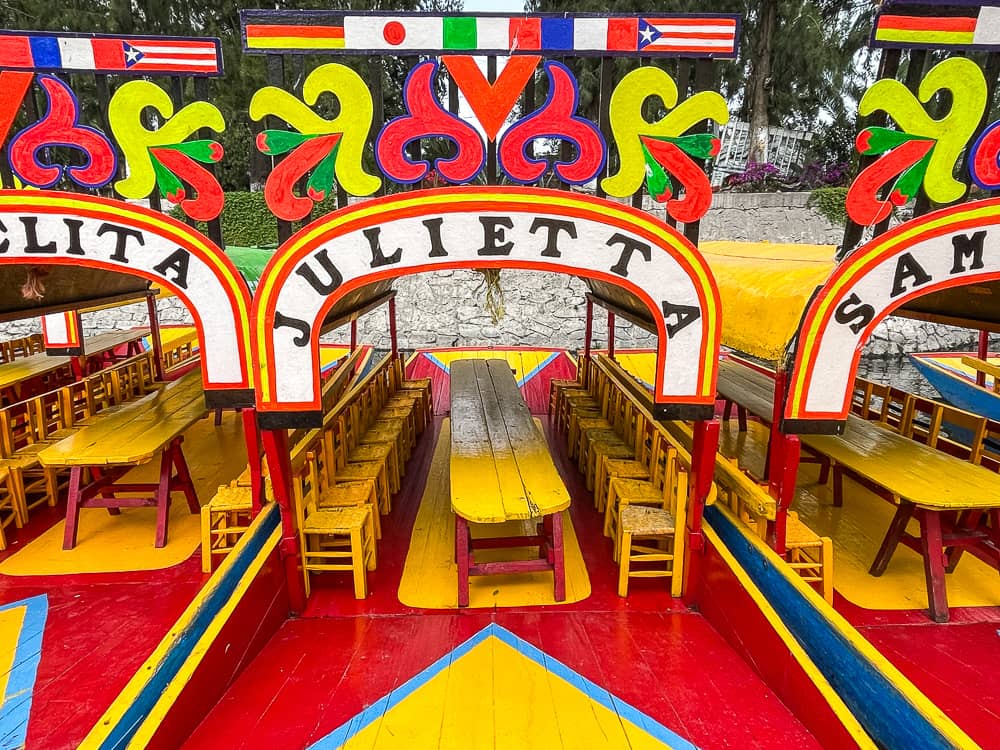 Colorful (mostly red and yellow), decorated flat-bottomed boats, furnished with a table and chairs.