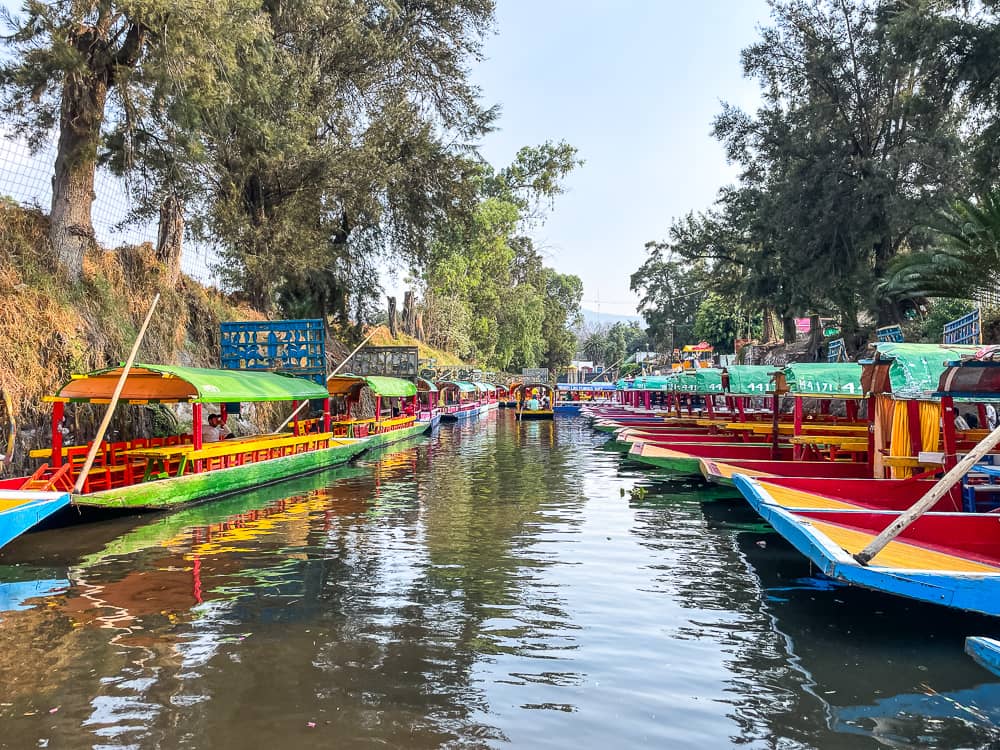 A canal lined with colorful flat-bottomed boats on either side. 