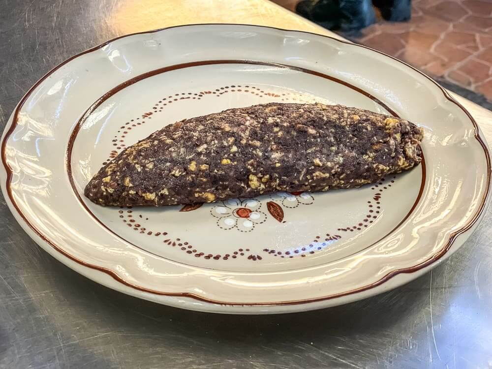 A brown and yellow oblong bean and egg mixture sits on a white plate with brown design.