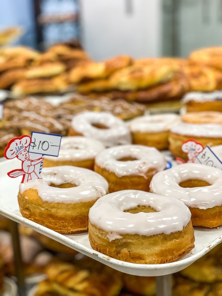 A tray full of donuts with white glaze. There is a sign with the image of a little red chef holding a sign that says 10.