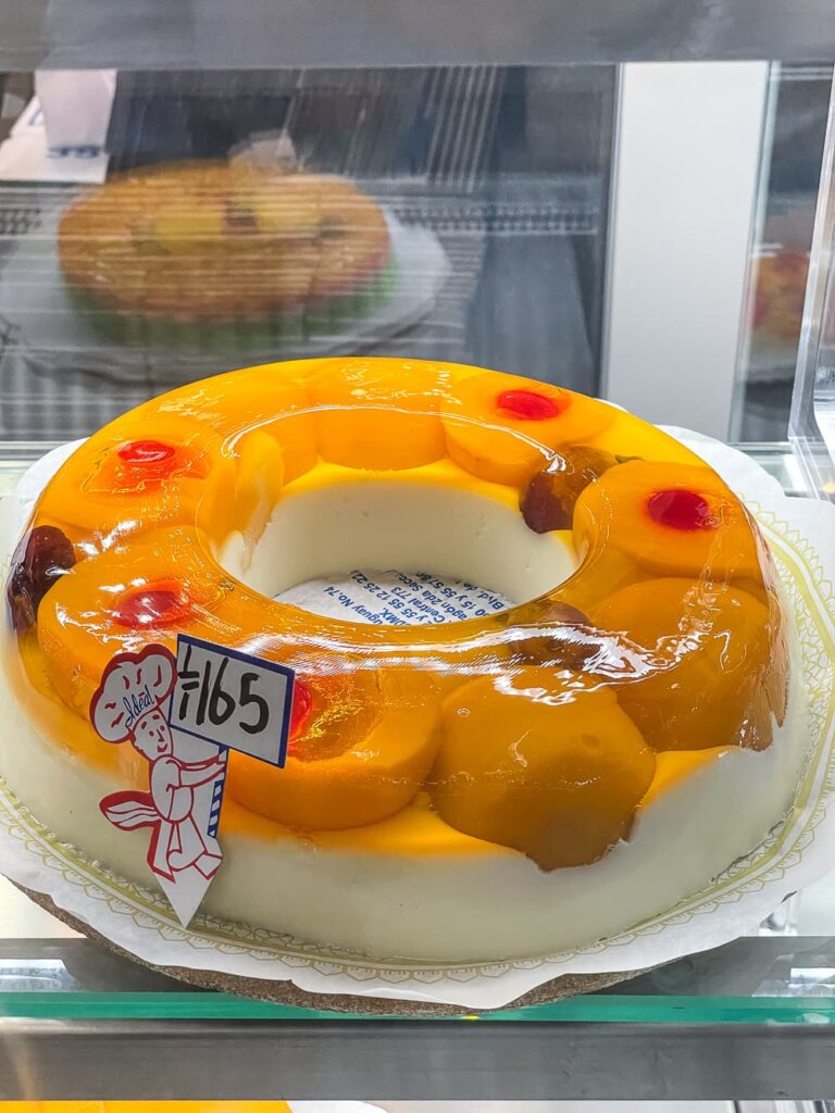 A bright orange ring of gelatin with large orange fruits with small red cherries. There is a sign with the image of a little red chef holding a sign that says 165.