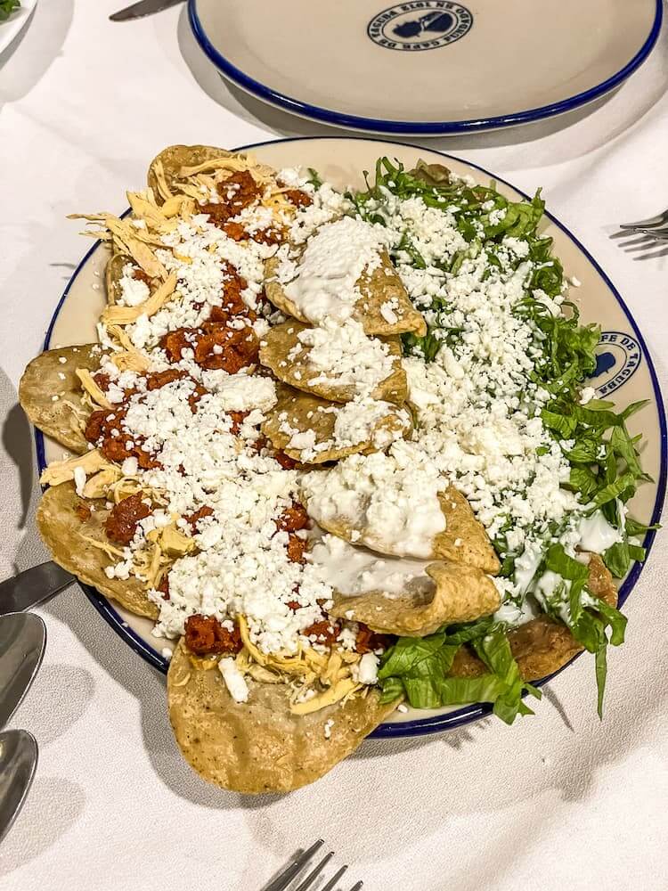 A blue and white plate laden with corn snacks topped with lettuce and cheese.