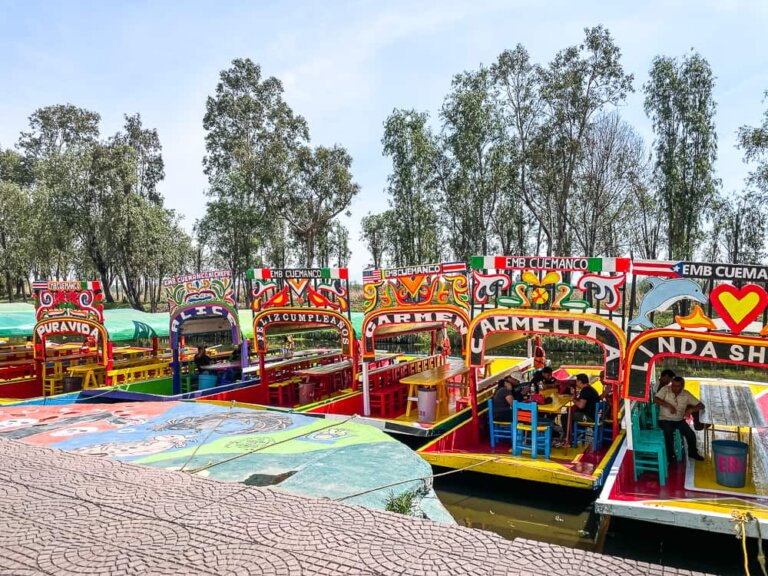 A row of colorful boats against the concrete dock. Each boat has an arch over the entrance with a different name.