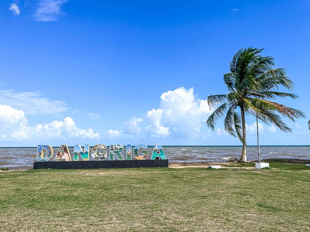 A big sign on a grassy lawn with concrete letters spelling DANGRIGA. There is a palm tree on the right